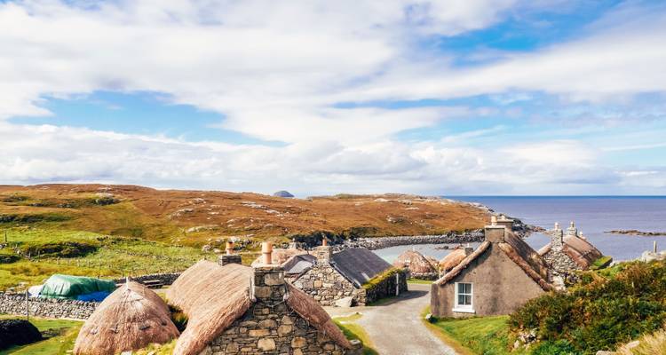 Cottages traditionnels en pierre au bord de la mer avec un ciel bleu.