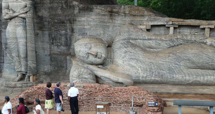 Touristen betrachten große liegende Buddha-Statue, die in Fels gemeißelt ist.
