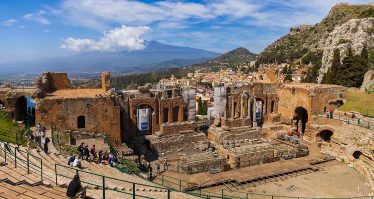 Ruïnes van een oud theater met een schilderachtig uitzicht op de stad en bergen.
