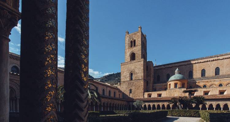 Kathedraal van Monreale met gedetailleerde buitenpatronen onder een blauwe hemel.