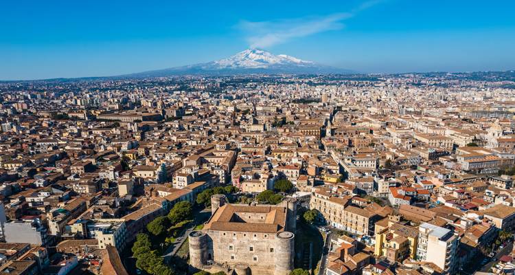 Luchtfoto van een stad met de Etna op de achtergrond.