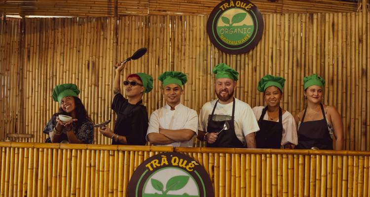 Groupe de personnes portant des toques de chef devant un mur en bambou.