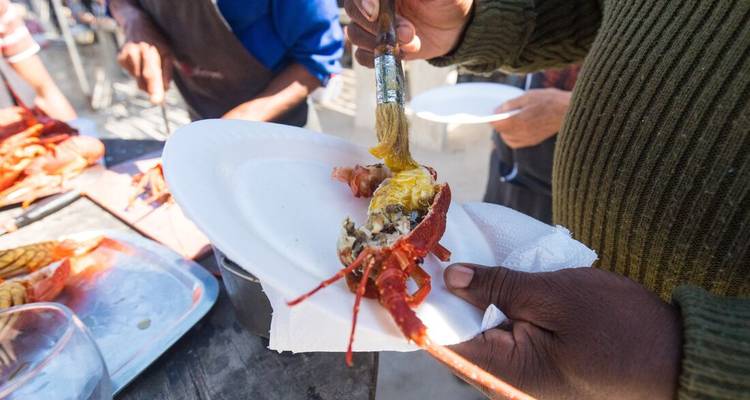 A person preparing seafood on a white plate outside.
