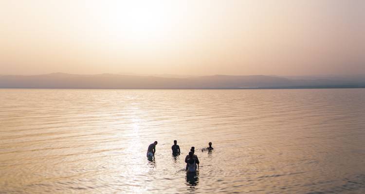 People swimming in a lake during sunset