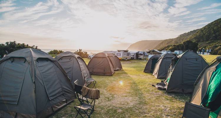 A campsite with tents and caravans near a coastal area.