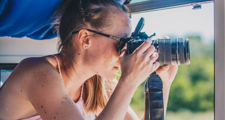 Person taking a photograph through a window.