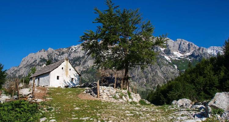 Kleines Haus auf einem Hügel mit einem großen Berg in der Ferne.