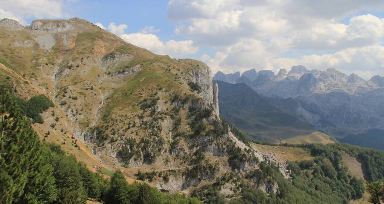 Gebirgszug mit sanften Hügeln und dramatischen Gipfeln in der Ferne.