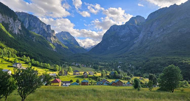 Idyllische Tallandschaft mit bunten Häusern und Bergpanorama.