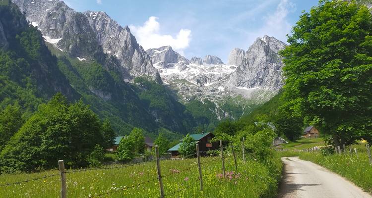 Straße durch ein Tal mit hohen Gipfeln und Grünflächen.