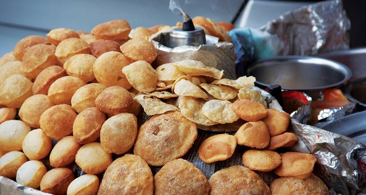 Assorted Indian snacks and a steaming cup of tea.