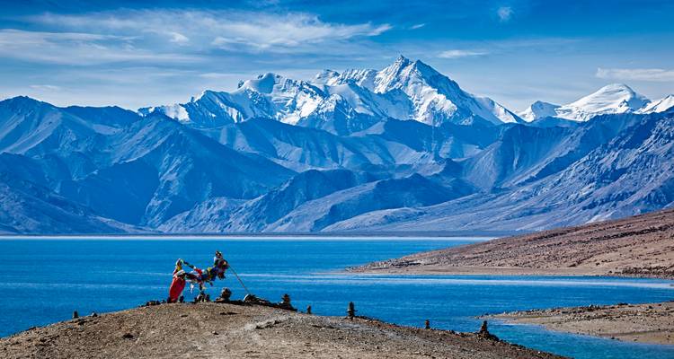 Randonneurs sur une colline avec des montagnes enneigées et un lac.