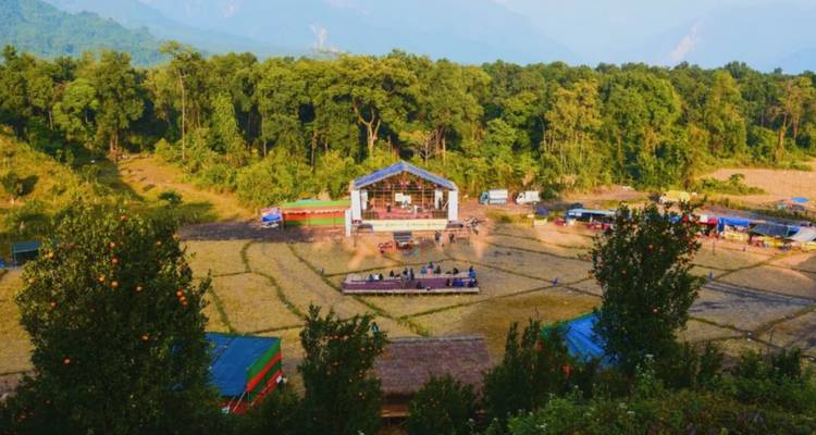 Scène de festival dans une zone rurale entourée d'arbres.
