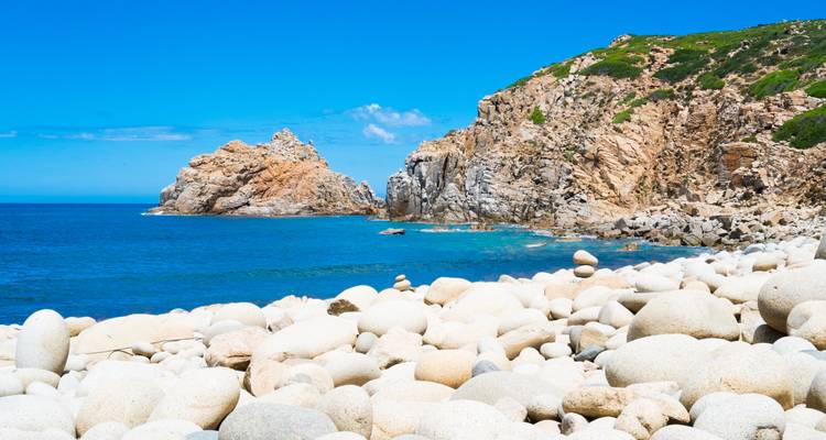 Plage rocheuse avec une eau bleue claire et des falaises.