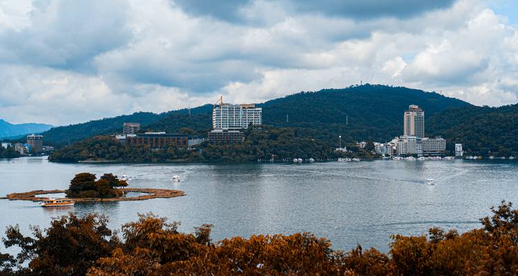 Scenic view of Sun Moon Lake with buildings and mountains in the background.