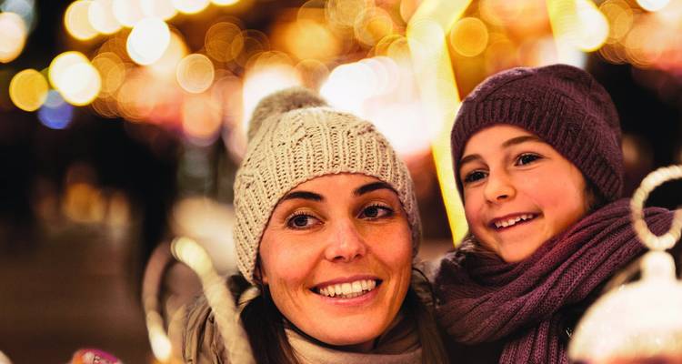 Mère et enfant profitant des festivités d'hiver avec des lumières décoratives en arrière-plan.