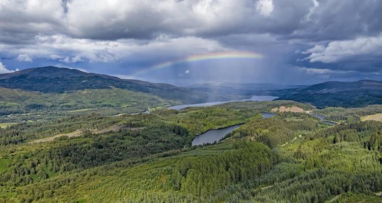 Une vue panoramique d'un paysage verdoyant luxuriant avec un arc-en-ciel dans le ciel.