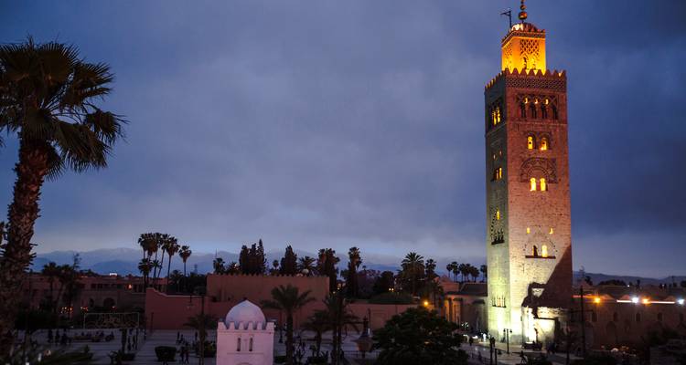 Tall minaret tower illuminated at night in a Moroccan city.