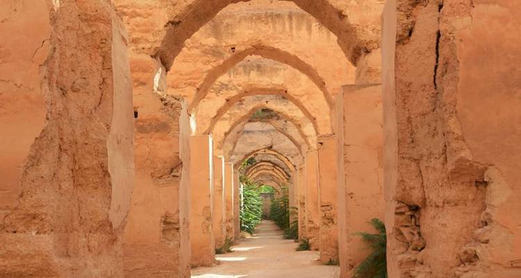 A long vaulted corridor of ancient earthen arches bathed in warm light.