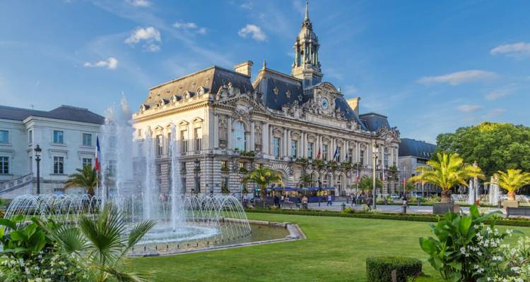 Hôtel de ville avec une fontaine dans un jardin paysager.