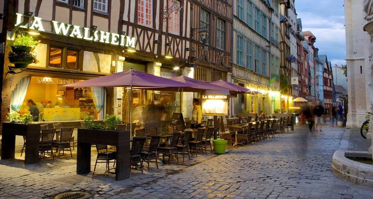 Zone de restauration en plein air dans une rue pavée pendant la soirée.