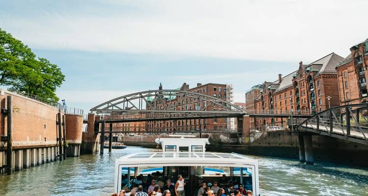 Canal with a tour boat and industrial-style buildings.