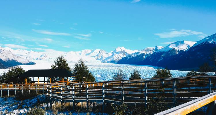 Glacial landscape with mountains and a wooden walkway.