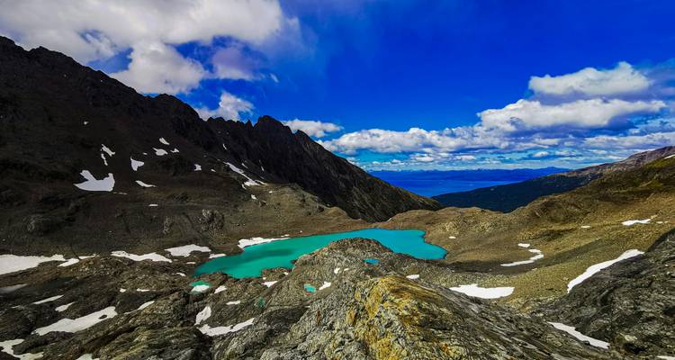 Lac entouré de montagnes rocheuses saupoudrées de neige.