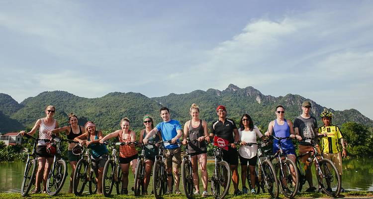 A group of cyclists posing with mountains in the background.