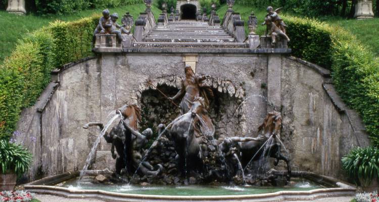 Detailed fountain with sculptures in garden setting.