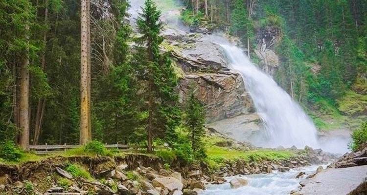 Waterfall cascading down rocky terrain amid lush forest.