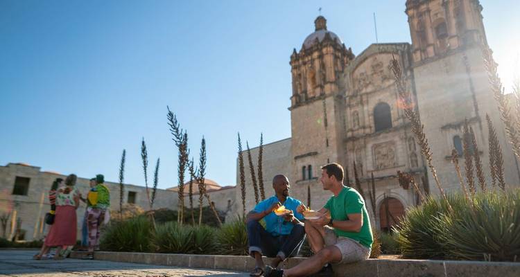 Deux hommes mangeant devant un bâtiment historique.