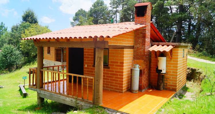 Une petite cabane en briques entourée d'une végétation luxuriante et d'un ciel dégagé.