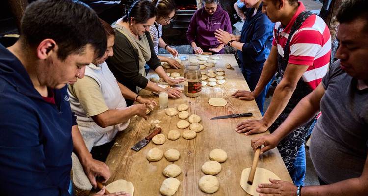 Un groupe de personnes préparant de la pâte dans une cuisine communautaire.