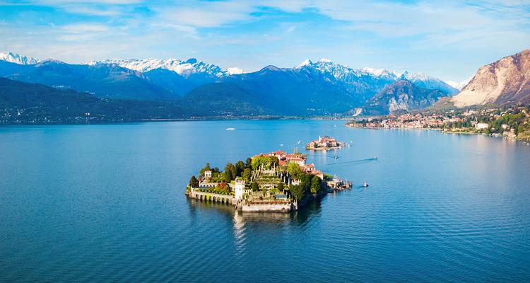 Île isolée avec des bâtiments et des montagnes au-delà d'un lac.