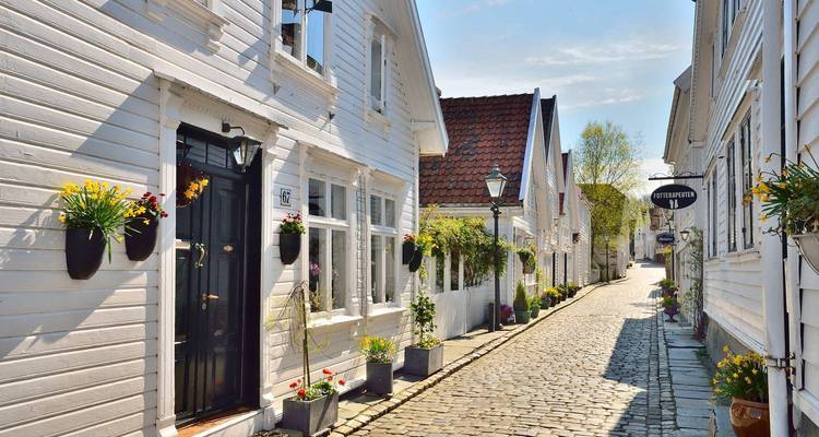 Quaint cobblestone street with white wooden houses.
