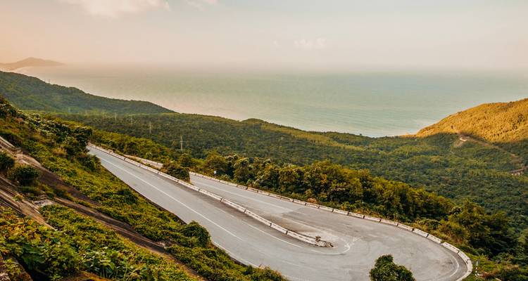 Route de montagne sinueuse avec vue sur l'océan.