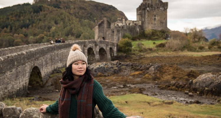 Pont de pierre historique avec un château et des touristes.
