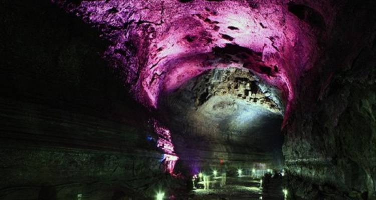Illuminated cave interior with colored lights on the ceiling.