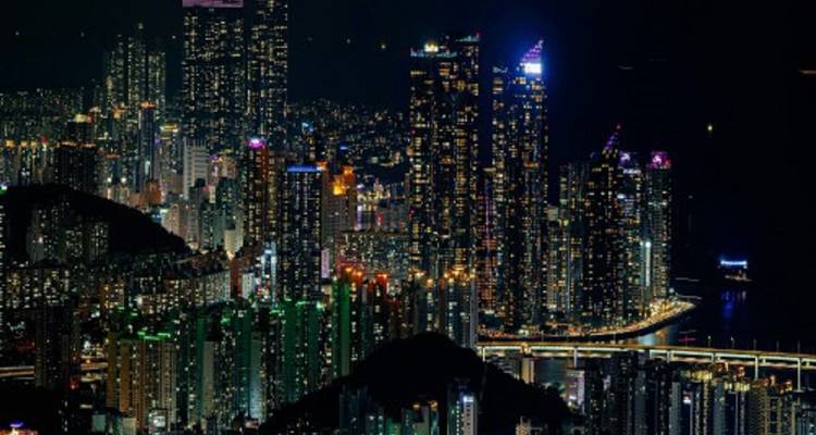 Night view of a city with illuminated skyscrapers and a bridge.