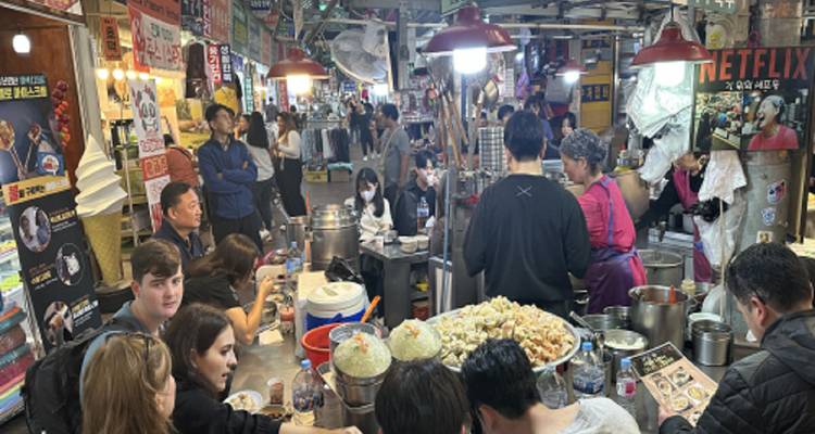 Busy indoor market scene with people dining and shopping.