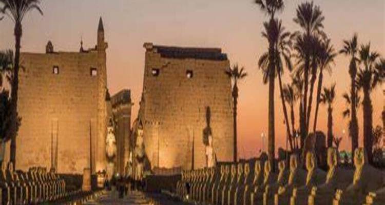 Camino ceremonial bordeado de estatuas que conduce a un templo al atardecer.