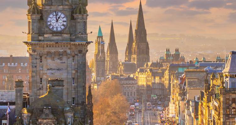 City skyline with clock tower and churches at sunset.