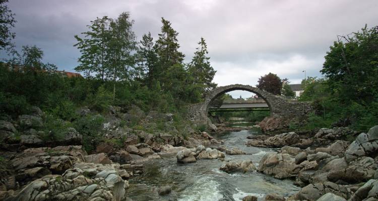 Stone arched bridge over a rocky river.