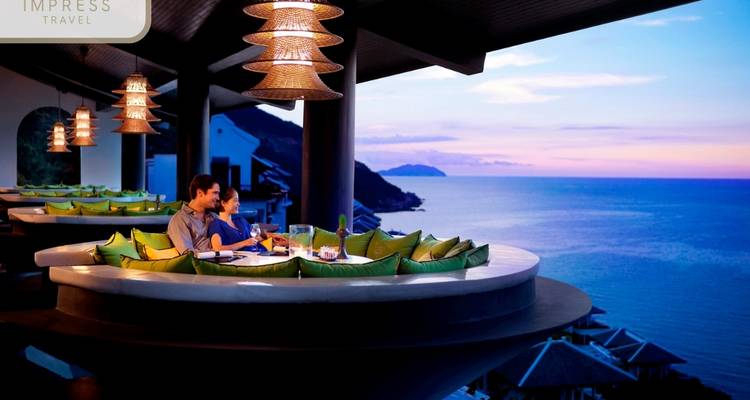 Des gens qui dînent dans un restaurant avec vue sur l'océan au coucher du soleil.