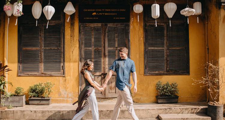 Couple marchant devant un bâtiment jaune rustique avec des lanternes.