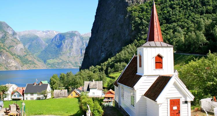 Une petite église surplombant un fjord avec un paysage montagneux.