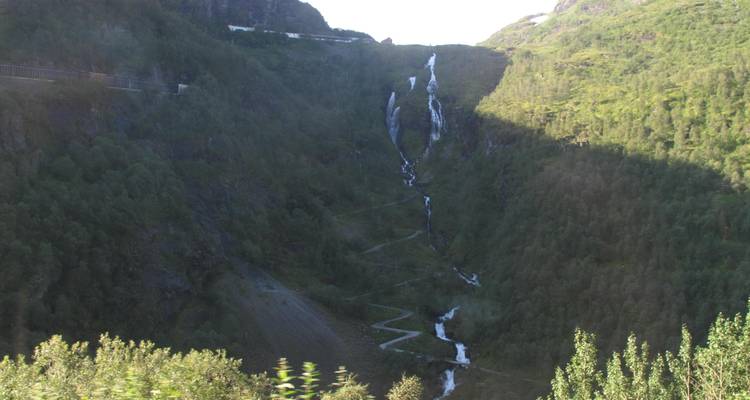 Une cascade qui dévale le flanc escarpé d'une montagne entourée d'une végétation luxuriante.