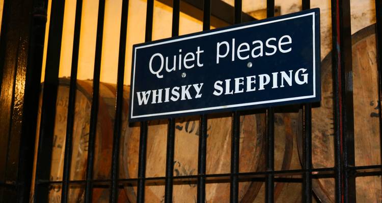 Sign reading 'Quiet Please Whisky Sleeping' in a distillery.