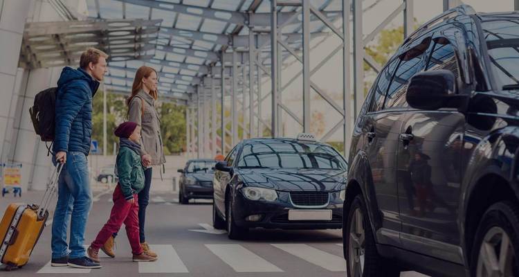 Une famille traversant la rue à un aéroport avec des voitures.